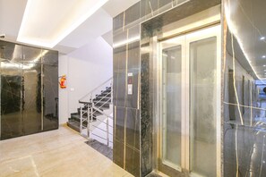 A modern interior with a marble staircase and elevator, a fire extinguisher, and a clean, minimalist design. - Fabhotel Lake View Iii (Indore)