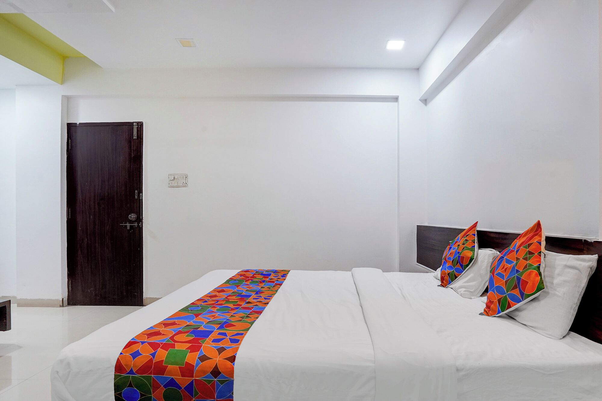 Een hotelkamer met een bed, een deur en een witte muur.