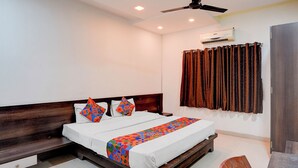 A bedroom with a bed, a ceiling fan, an air conditioning unit, and a window with curtains. - Via Paradise Stay Inn (Mawal)