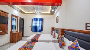 Quarto de hotel com duas camas, televisão, guarda-roupa e ventoinha no teto.