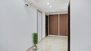 A hallway with a potted plant, a door, and a sliding glass door. - Fabhotel Bellmore Stay & Homes (Gurugram)