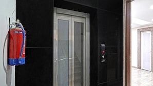 A fire extinguisher mounted on a wall next to a door. - Fabhotel Bellmore Stay & Homes (Gurugram)