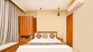 Een hotelkamer met een groot bed, een houten garderobe, nachtkastje en een airconditioner.