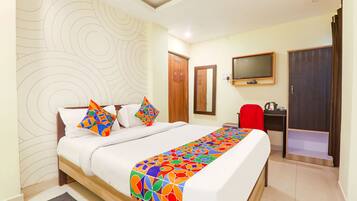 A hotel room with a bed, a TV, a desk, and a wardrobe.