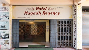 The front of Hotel Magadh Regency with a checkered floor pattern inside, a metal gate, and a green mat at the entrance. - Fabhotel Magadh Regency (Patna)