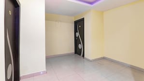A hallway with a door on the right, a light-colored floor, and a ceiling with a purple light strip. - Fabhotel Magadh Regency (Patna)