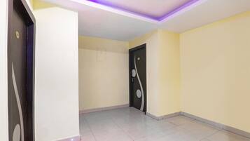 A hallway with a door on the right, a light-colored floor, and a ceiling with a purple light strip.