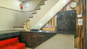Un comptoir d’accueil avec une enseigne indiquant « Hôtel Rama Inn », un extincteur et une horloge murale.