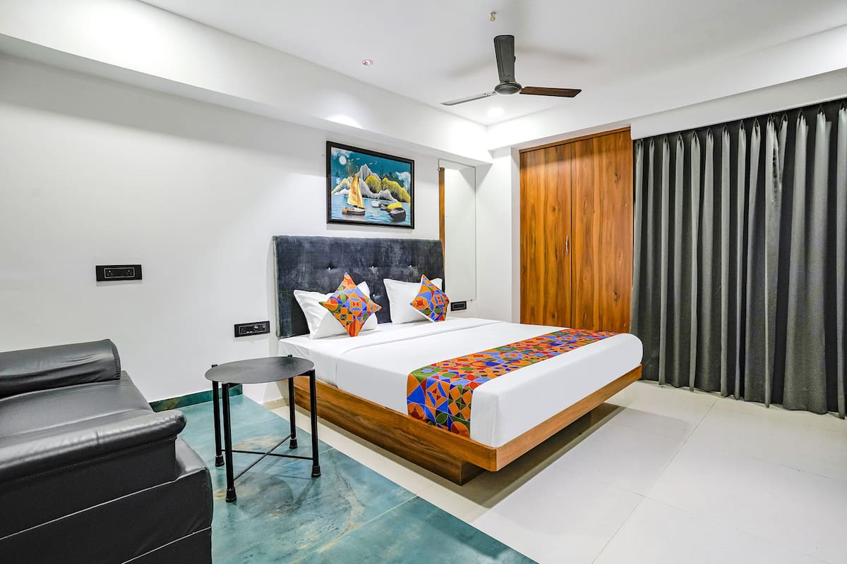 Una habitación de hotel moderna con una cama grande, una mesita, un sofá y un cuadro en la pared.