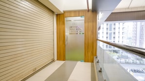 A hotel entrance with a closed shutter door, a visible phone number, and a view of the street outside.