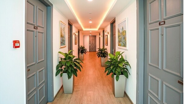 A hallway with grey doors, numbered 306 and 308, and potted plants on either side. - Fabhotel The Luxe Inn (New Delhi)