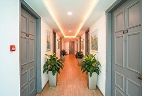 A hallway with grey doors, numbered 306 and 308, and potted plants on either side. - Fabhotel The Luxe Inn (New Delhi)