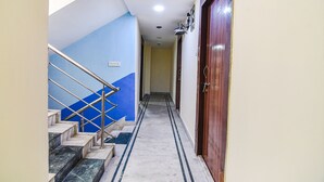 Un pasillo con una escalera de mármol, una puerta de madera y una pared azul.
