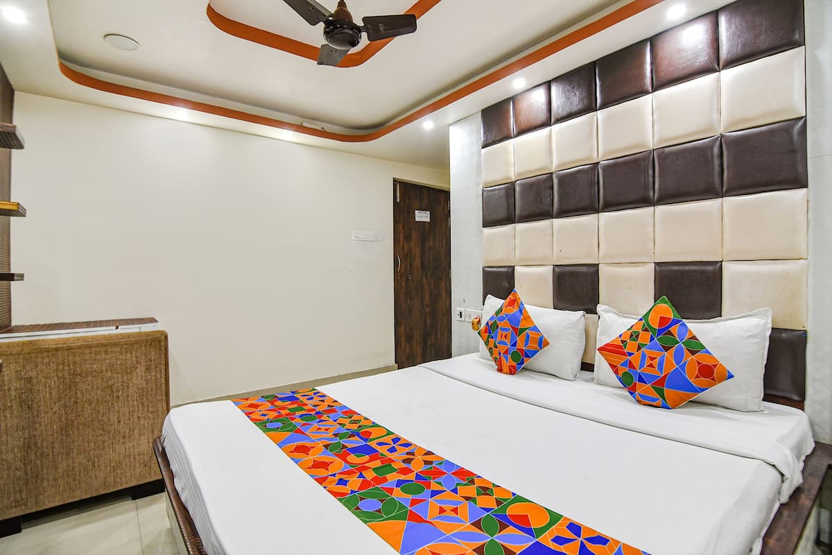 Habitación de hotel con cama, ventilador de techo, mesita de noche y puerta.