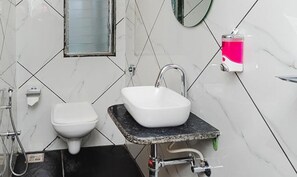 A bathroom with a white toilet, a white sink with a black countertop, and a mirror above the sink. - Fabhotel Airport Palace (Mumbai)