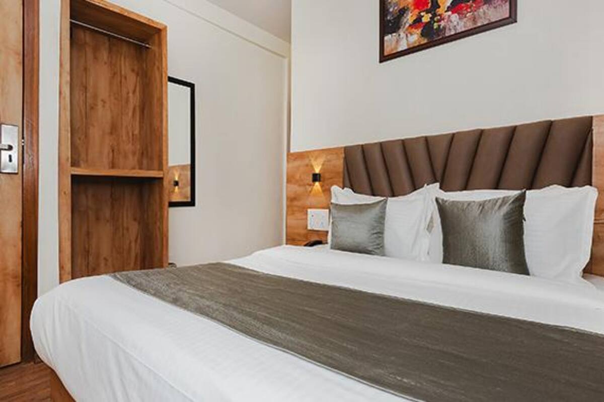 Una habitación de hotel con una cama grande, cabecera de madera y un cuadro en la pared.