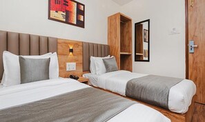 A hotel room with two beds, a wooden wardrobe, a nightstand, and a wall-mounted light fixture. - Fabhotel Airport Palace (Mumbai)