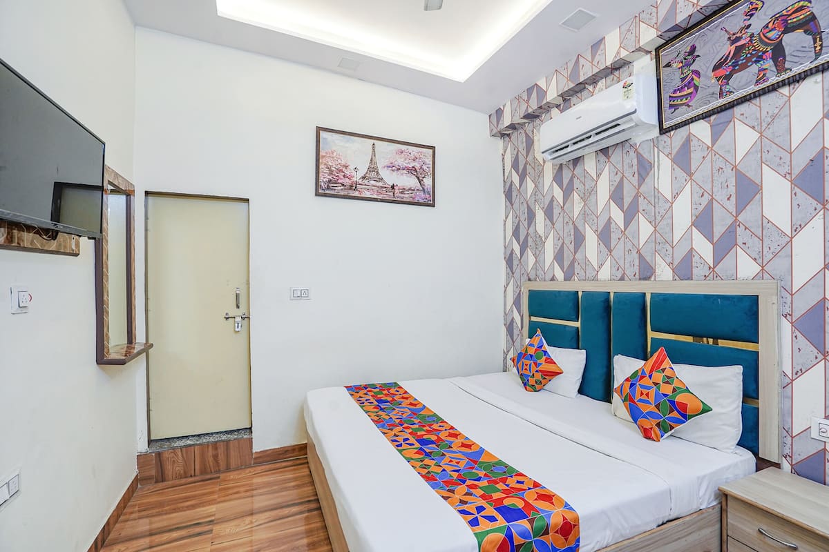 Una habitación de hotel con cama, mesita de noche, espejo y puerta.