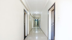 A long, narrow hallway with doors on both sides, leading to a room at the end. - Via Yashraj Inn (Pune)