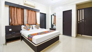 A modern bedroom with a bed, nightstand, dresser, and a ceiling fan. - Via Yashraj Inn (Pune)