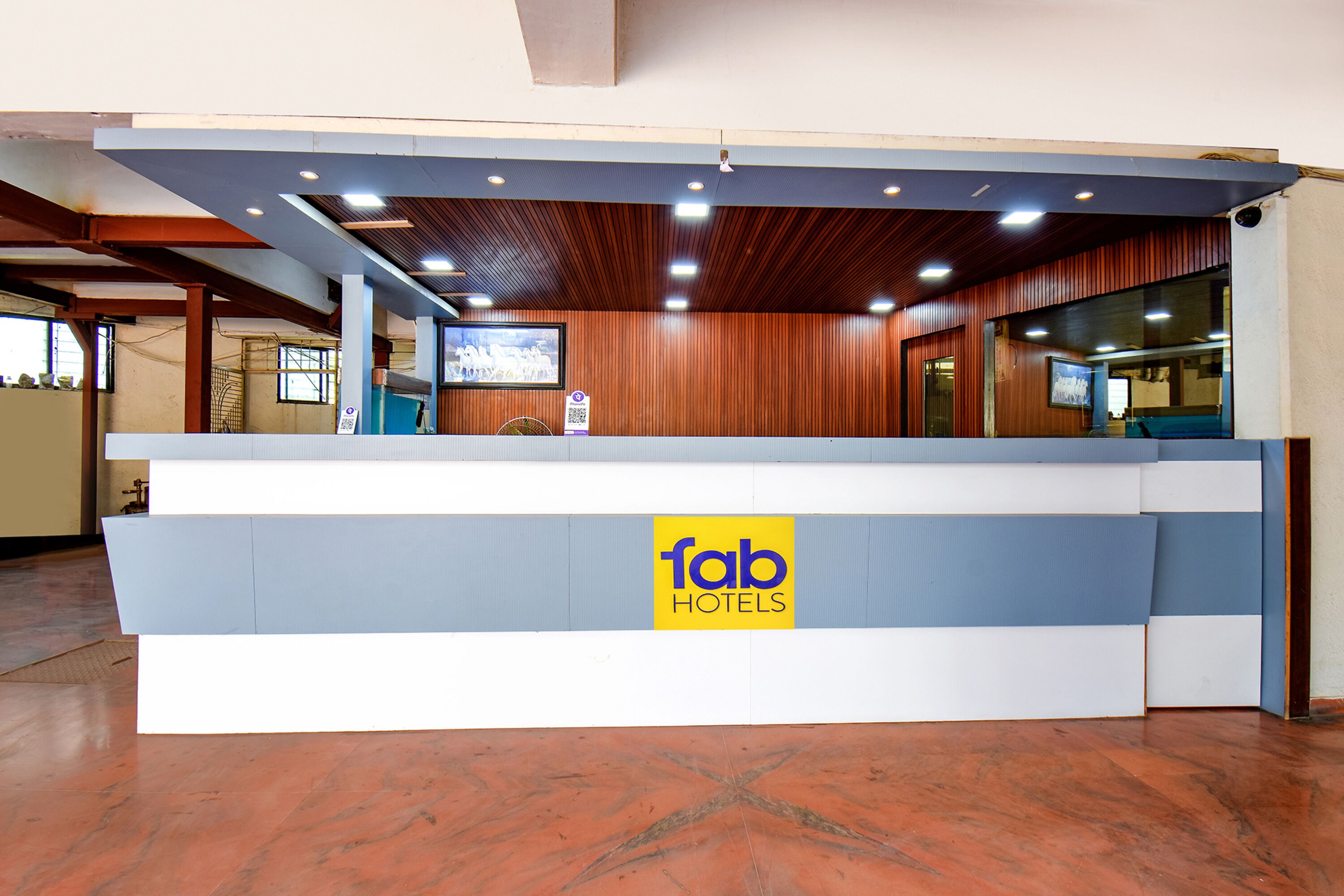 Una mesa de recepción con el logo 'fab hotels', paneles de madera en las paredes y suelo de baldosas.