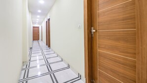A corridor with a checkered floor, wooden doors, and recessed ceiling lights. - Fabhotel Starlight (New Delhi)
