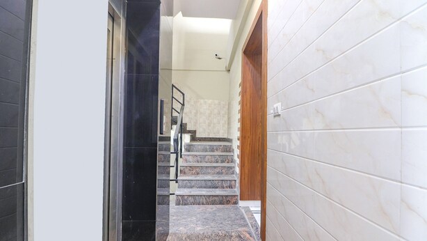 A hallway with a marble staircase leading to a landing. - Fabhotel Starlight (New Delhi)