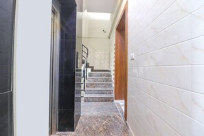 A hallway with a marble staircase leading to a landing.