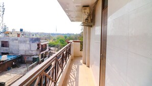 A balcony with a view of a residential area, a tiled wall, and a utility box. - Fabhotel Starlight (New Delhi)