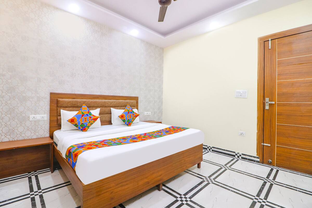 A neatly arranged bedroom with a wooden bed, two pillows, a bedside table, and a door.
