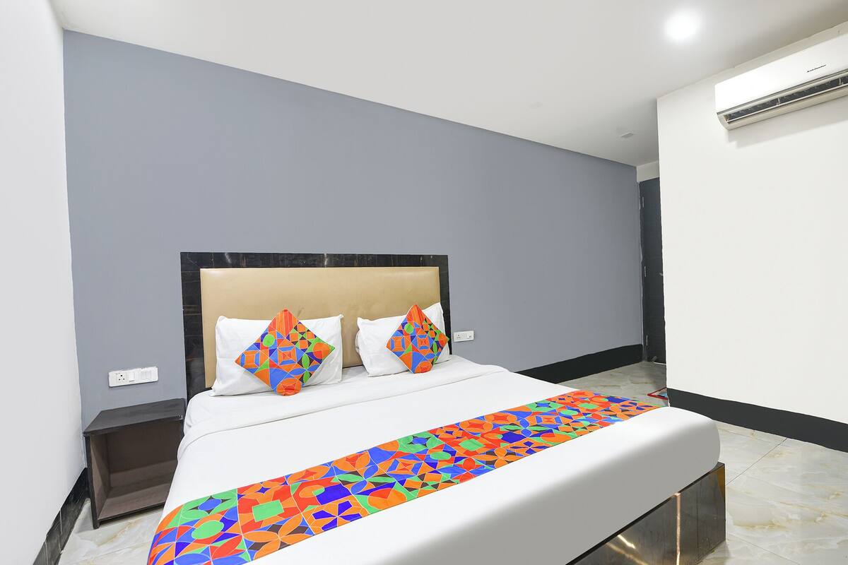 Une chambre d’hôtel comprenant un lit, une tête de lit, une table de chevet et un appareil de climatisation.
