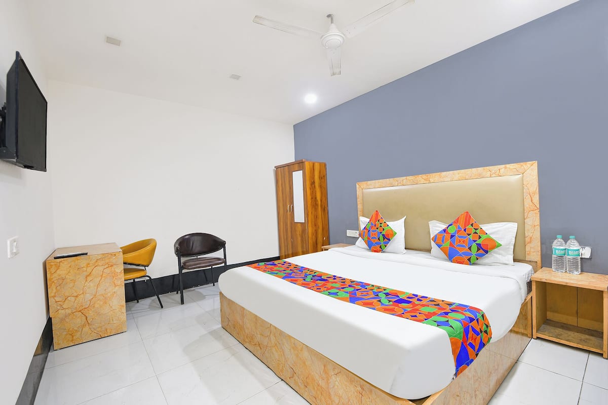 A hotel room with a bed, a desk, a chair, a wardrobe, and a TV mounted on the wall.