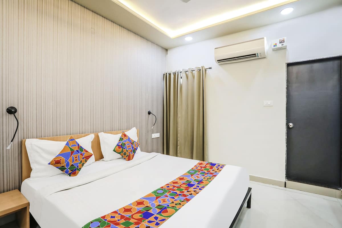 Una habitación de hotel con una cama, cortinas, un aire acondicionado y una puerta.
