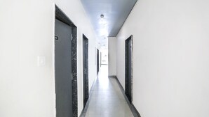 En lång, smal hall med vita väggar och mörka dörrkarmar, som leder till ett ljust rum längst in.