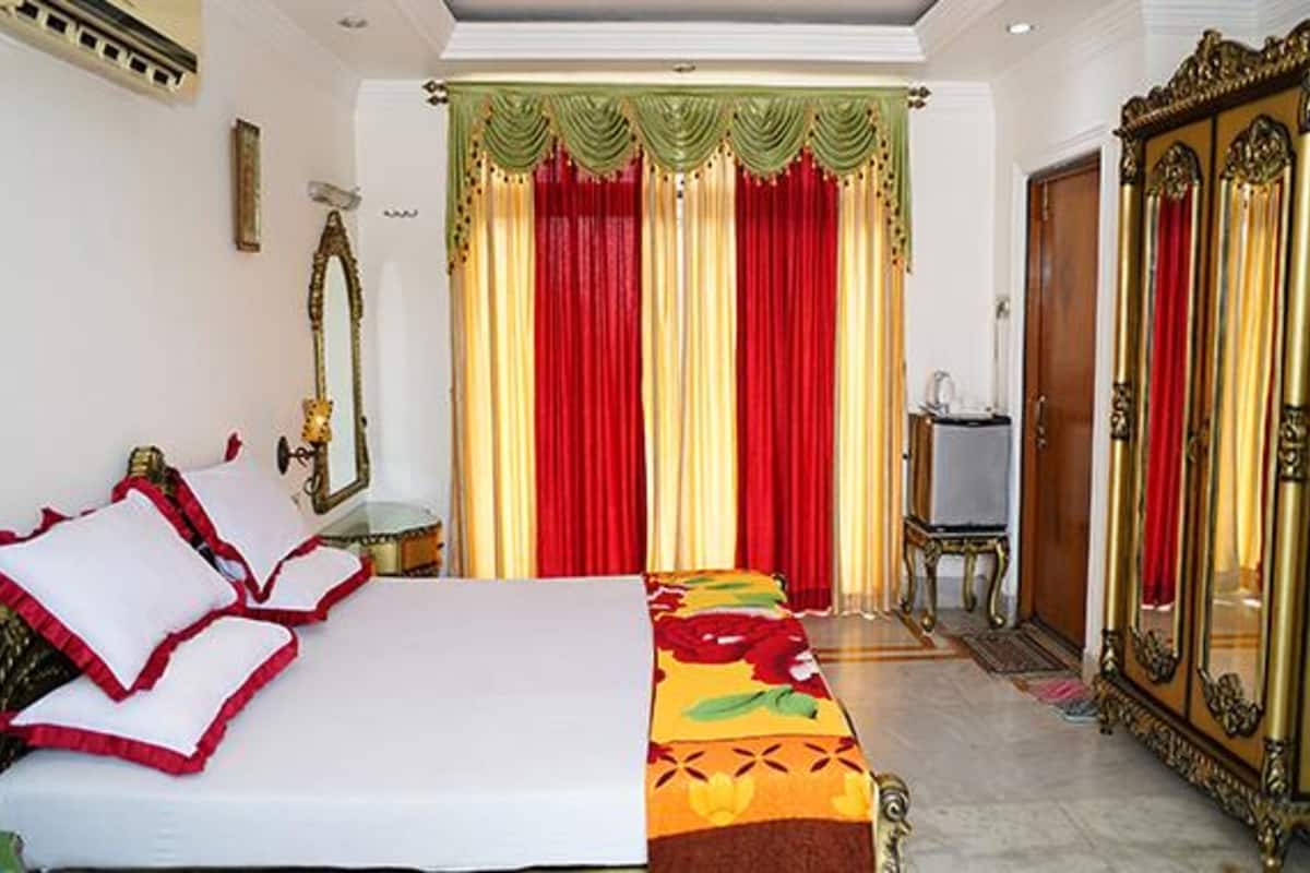 A hotel room with a bed, a mirror, a wardrobe, and a desk.