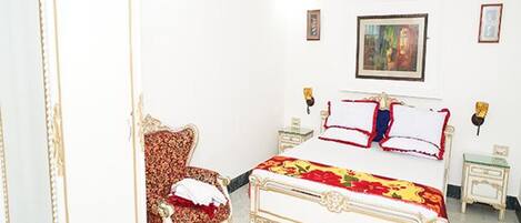 A bedroom with a bed, a chair, and a painting on the wall.