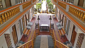 A corridor with benches and a central walkway, flanked by columns and a staircase leading to an upper level. - FabHotel Prime Indeedcare (Kakdwip)