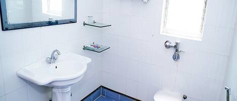 A bathroom with a pedestal sink, a toilet, and a small window.