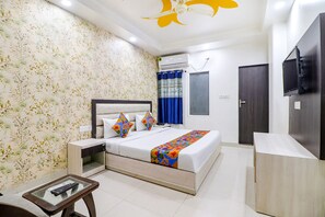 A hotel room with a bed, bedside tables, a TV, and a ceiling fan.