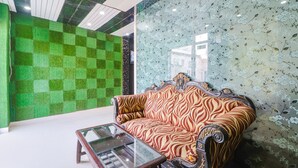 A room with a green checkered wall, a floral wallpaper, a patterned sofa, and a glass-top table. - Fabexpress Gross Aero (New Delhi)