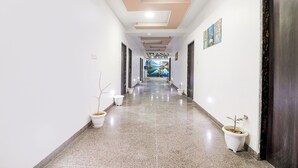 A long, narrow hallway with a polished floor, white walls, and a ceiling with recessed lighting. There are potted plants placed along the sides. - Fabexpress Gross Aero (New Delhi)