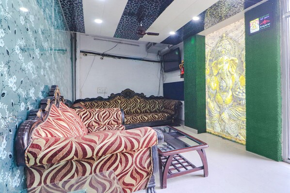 A living room with a patterned sofa, a glass coffee table, and a wall mural.
