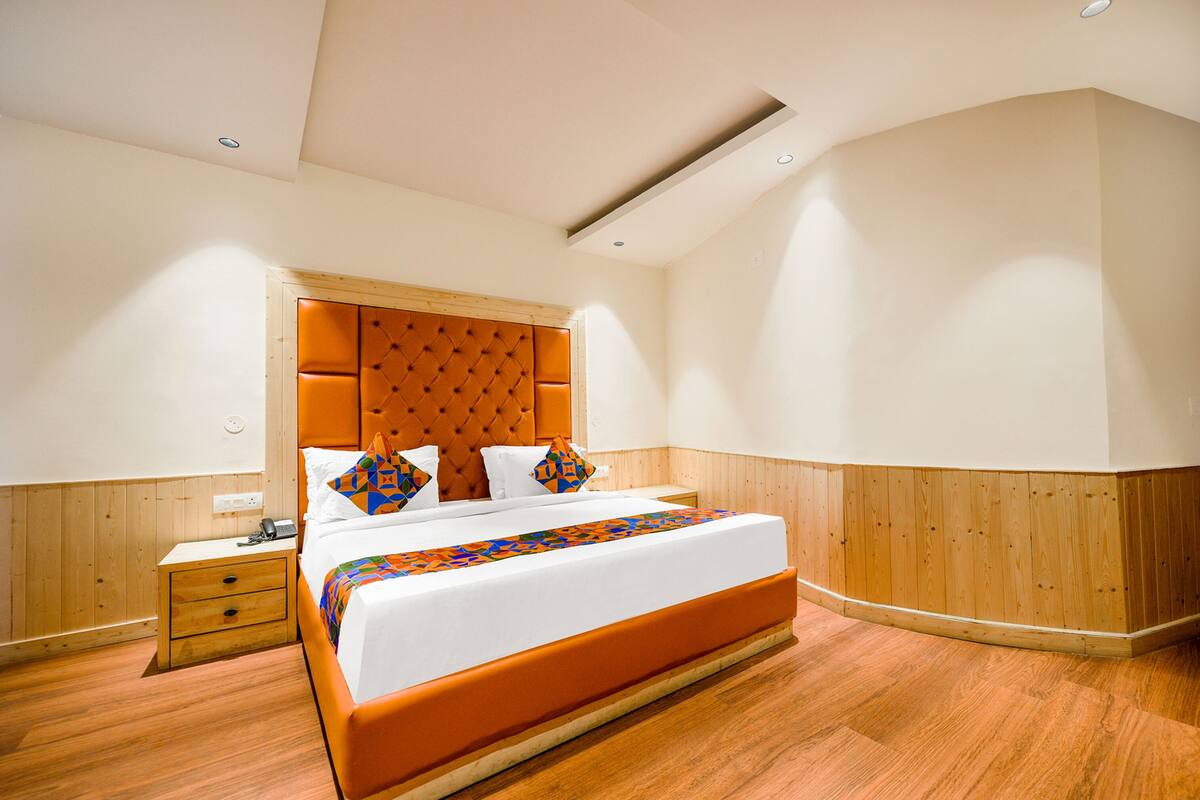 A bedroom with a large bed, wooden paneling on the walls, and a modern ceiling design.