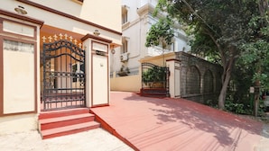 A gated entrance with a red mat leading to a building with a number plaque.