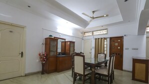 A dining area with a wooden table and chairs, a ceiling fan, and a decorative vase with flowers.