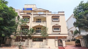 A multi-story hotel with a beige facade, balconies, and a gated entrance.