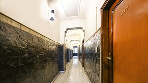 Un couloir au sol et aux murs recouverts de marbre, qui mène à une porte portant le numéro 247.