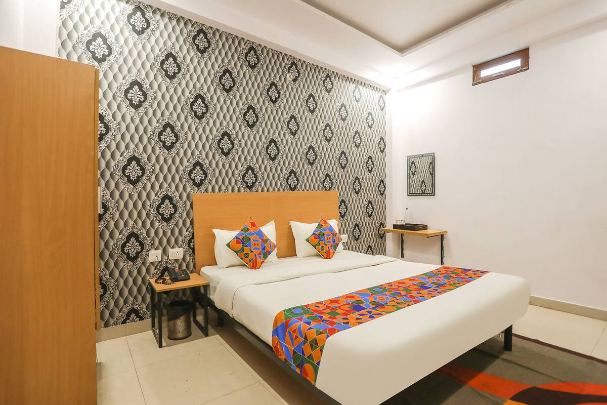 A neatly arranged hotel room with a bed, a nightstand, and a wall with patterned wallpaper.