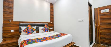 A neatly made bed with a colorful geometric-patterned blanket, a wooden headboard, and two decorative pillows.