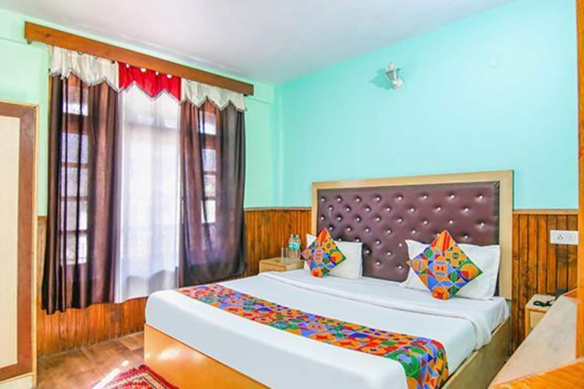 A bedroom with a bed, curtains, a headboard, and a nightstand.